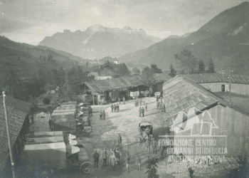 Autoparco militare a Calalzo, sullo sfondo la chiesa di S. Giorgio a Domegge e la catena Tudaio Brentoni. 1917.